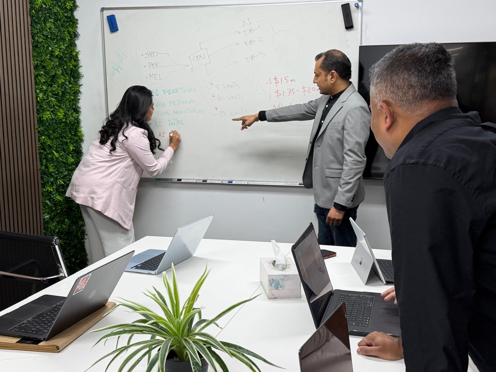 Team members working through ideas at a whiteboard